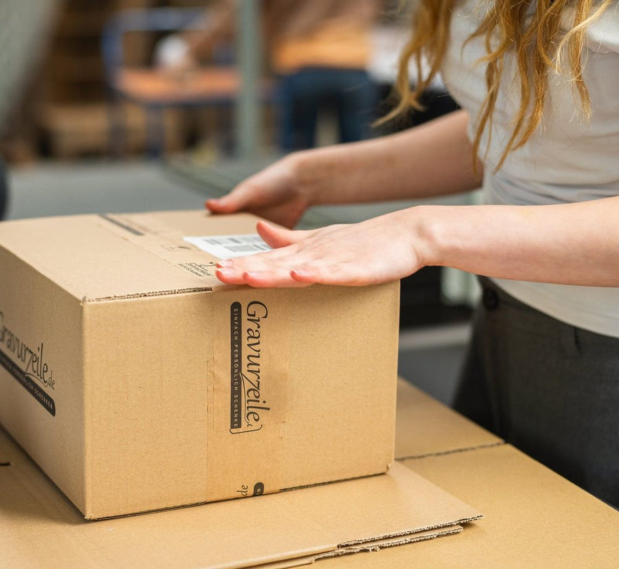 Am Packtisch wird ein GRAVURZEILE-Karton verschlossen