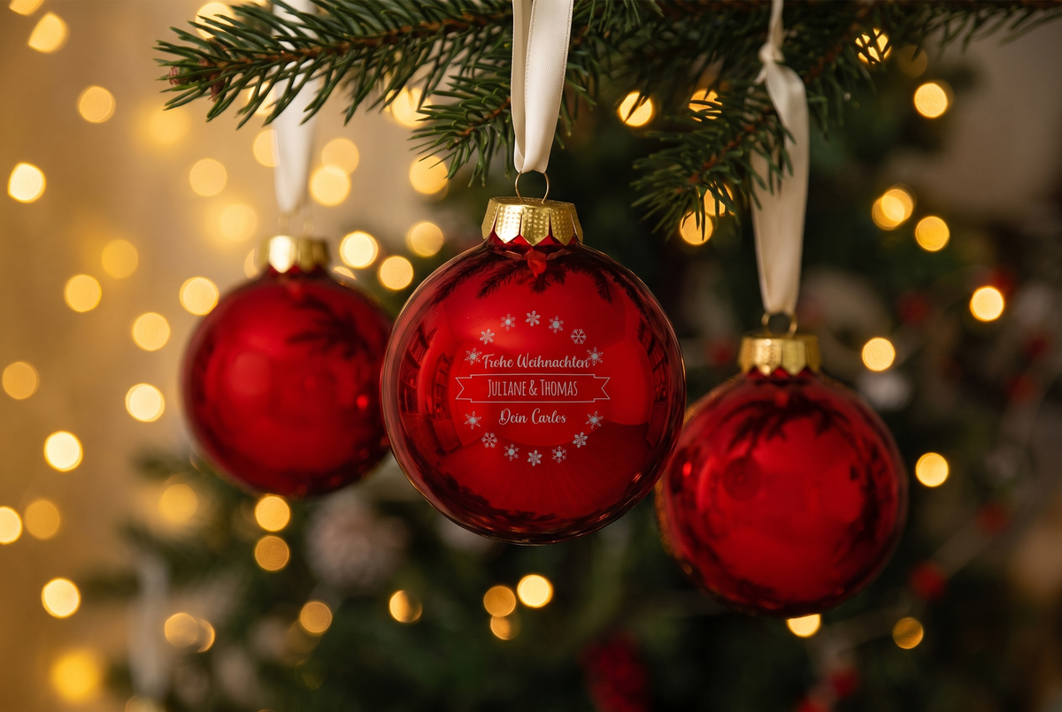 Drei rote Weihnachtskugeln aus Glas am Baum, die vordere mit Gravur, Namen und Wunschtext