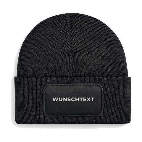 Schwarzes Beanie mit Patch und weißem Wunschtext, Freisteller