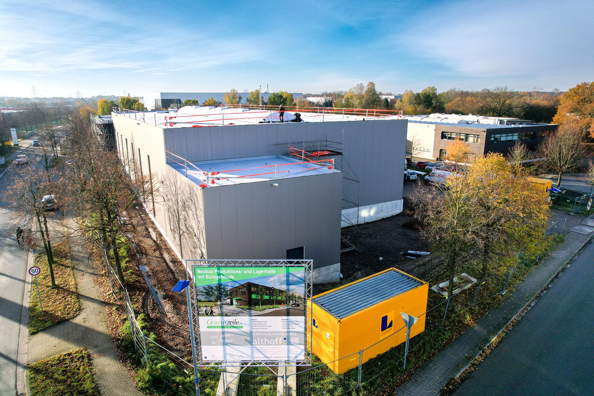 Neubau von GRAVURZEILE im November 2023 mit geschlossener Fassade und Bauschild