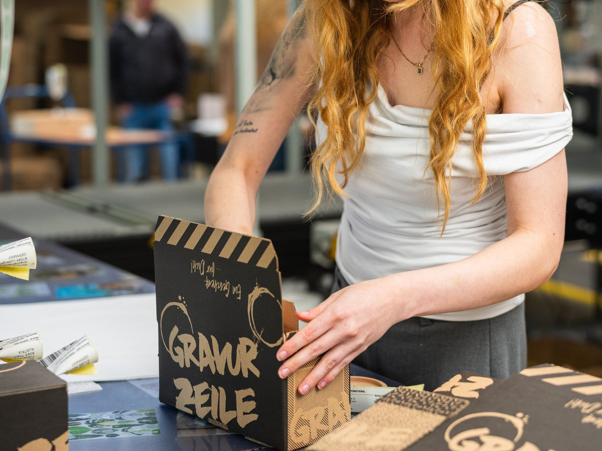 Am Packtisch werden GRAVURZEILE-Kartons gefaltet