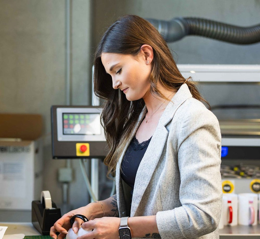 Mitarbeiterin in der Produktion bereitet Tassen für den Druck vor