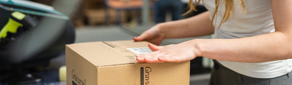 Am Packtisch wird ein GRAVURZEILE-Karton verschlossen