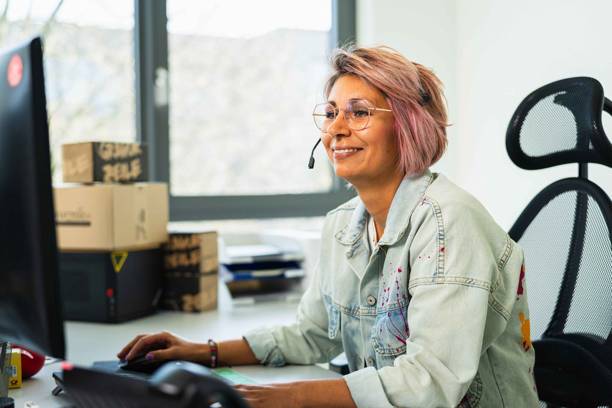 Mitarbeiterin im Kundendienst mit Headset am Arbeitsplatz
