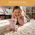 Mädchen lächelt Kuscheltier Schwein mit Namen an